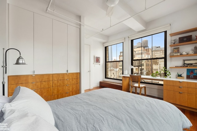 bedroom featuring hardwood / wood-style flooring, built in desk, and beamed ceiling