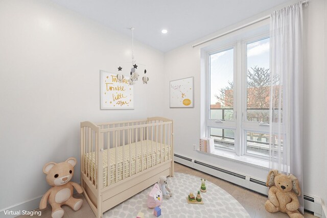 bedroom featuring baseboard heating, a crib, recessed lighting, and baseboards