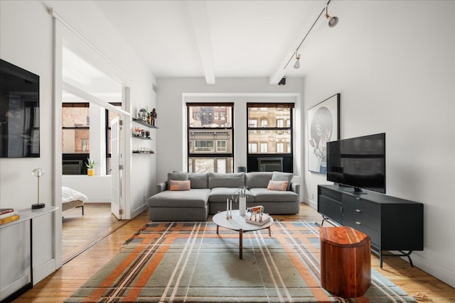 living room with beam ceiling, rail lighting, baseboards, and wood finished floors