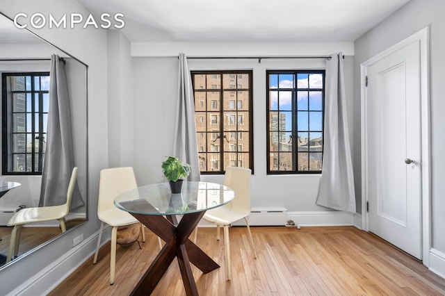 dining space featuring baseboards, light wood-style floors, and a baseboard radiator