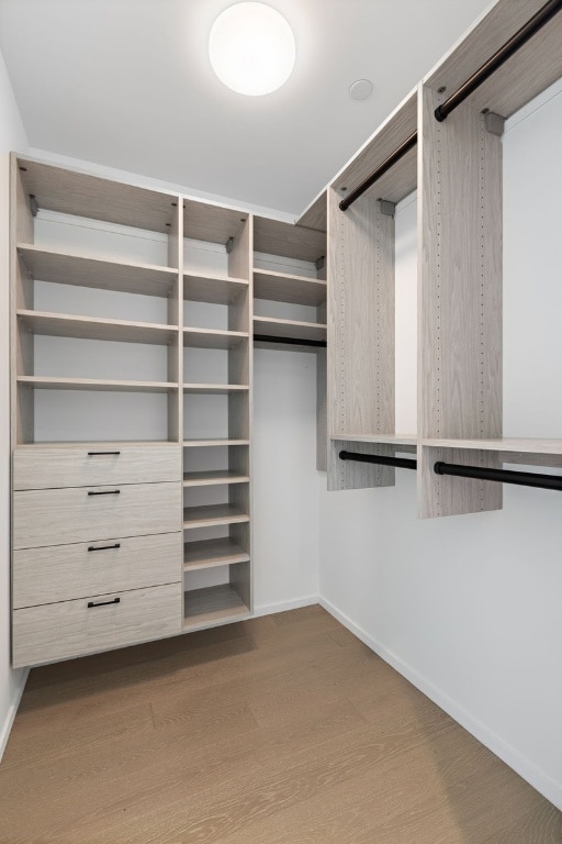 walk in closet with light hardwood / wood-style floors