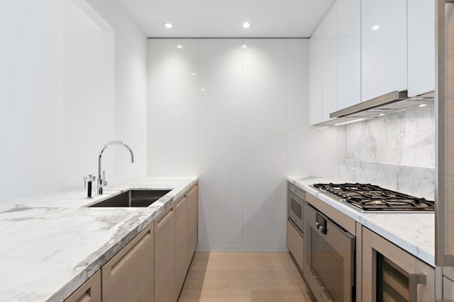 kitchen with sink, light stone countertops, stainless steel gas cooktop, and white cabinets