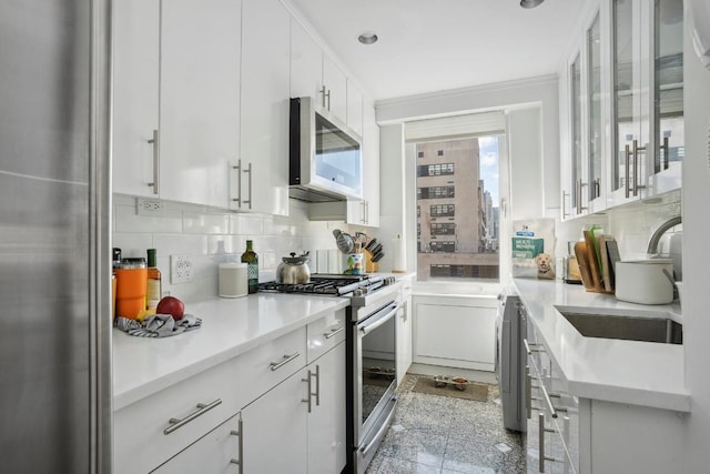 kitchen with decorative backsplash, stainless steel appliances, and white cabinets