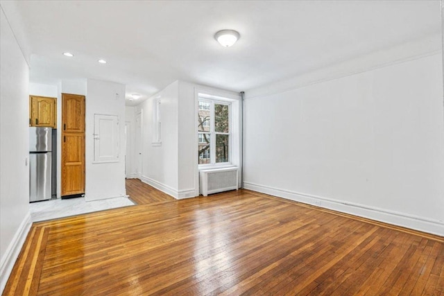 unfurnished living room featuring radiator heating unit and light hardwood / wood-style floors