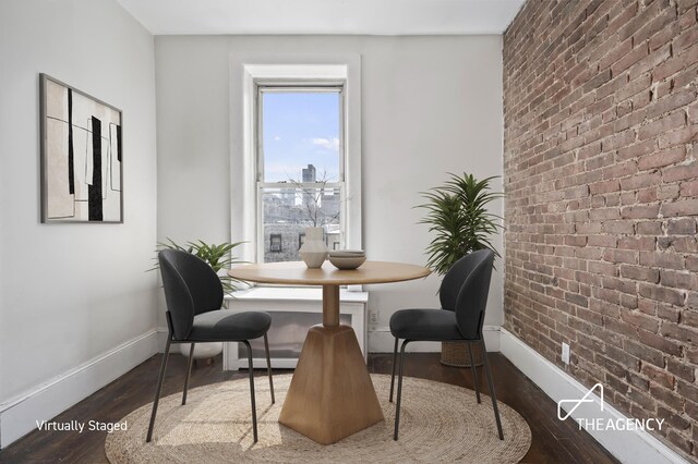 sitting room with brick wall and hardwood / wood-style floors