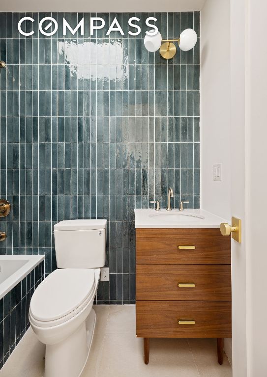 bathroom with vanity, tile walls, tile patterned floors, and toilet