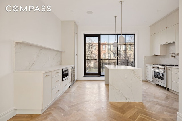 kitchen with decorative light fixtures, backsplash, a kitchen island, white cabinets, and high end range