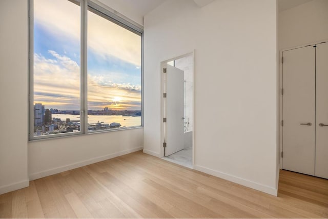 unfurnished bedroom with a water view and light wood-type flooring