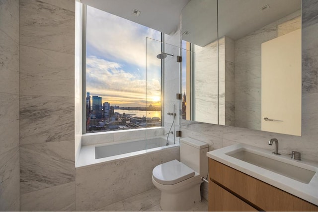 full bathroom featuring vanity, tiled shower / bath, tile walls, and toilet