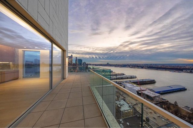 balcony at dusk featuring a water view