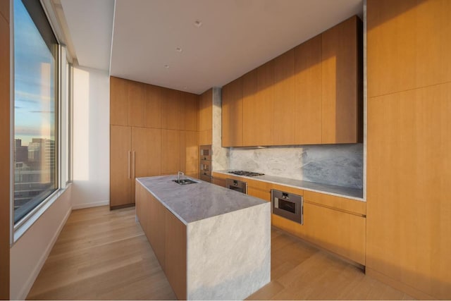 kitchen with tasteful backsplash, stainless steel gas stovetop, a kitchen island, and light wood-type flooring