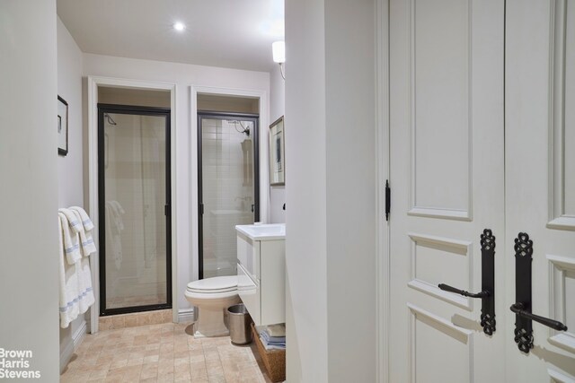 bathroom featuring a shower with door, vanity, and toilet