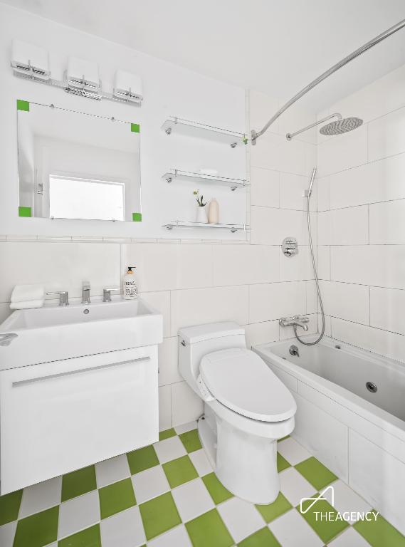 full bathroom with vanity, tiled shower / bath combo, tile walls, and toilet