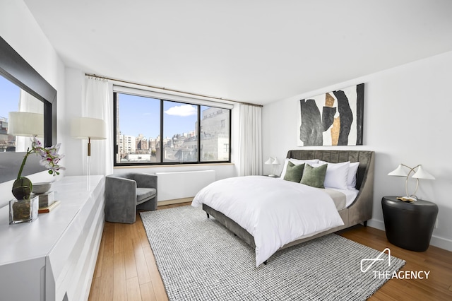 bedroom featuring a view of city, wood finished floors, and baseboards