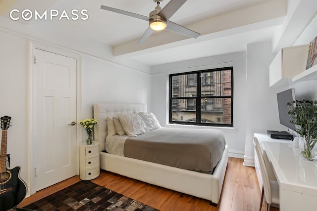 bedroom with beamed ceiling, wood finished floors, and a ceiling fan