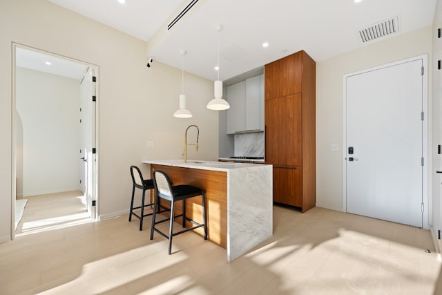 kitchen featuring a breakfast bar, decorative light fixtures, white cabinetry, sink, and kitchen peninsula