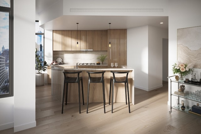 kitchen featuring modern cabinets, a breakfast bar area, decorative light fixtures, a peninsula, and backsplash