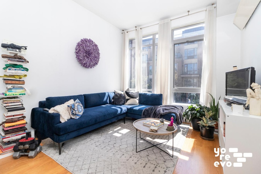 living room with a wealth of natural light, vaulted ceiling, and wood finished floors