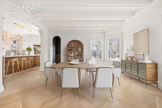 dining room featuring arched walkways and beam ceiling