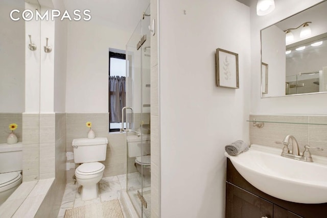 bathroom featuring a shower with door, vanity, tile walls, and toilet