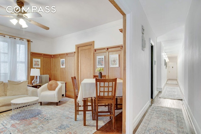 dining room featuring ornamental molding, baseboards, light wood finished floors, and a ceiling fan