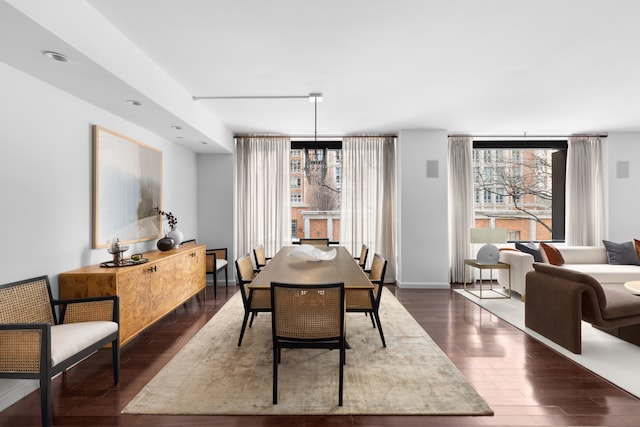 dining space featuring a healthy amount of sunlight, a notable chandelier, and dark wood-style flooring