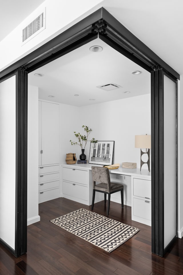 office area with dark wood-style floors, built in study area, and visible vents