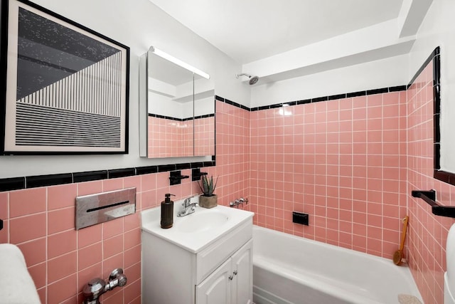 bathroom featuring tiled shower / bath, vanity, and tile walls