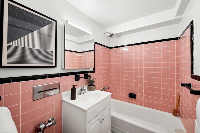 bathroom featuring tiled shower / bath, vanity, and tile walls