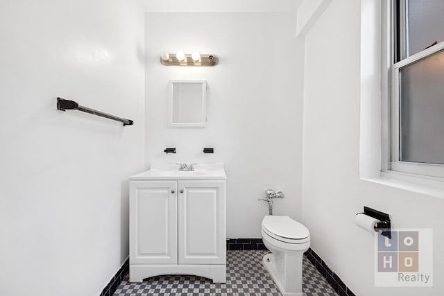 half bath with vanity, toilet, and baseboards