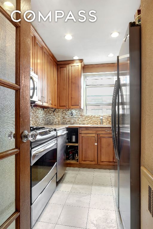 kitchen with decorative backsplash, light tile patterned flooring, and appliances with stainless steel finishes