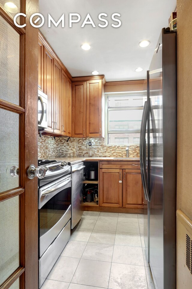 kitchen featuring stainless steel appliances, light tile patterned flooring, and backsplash