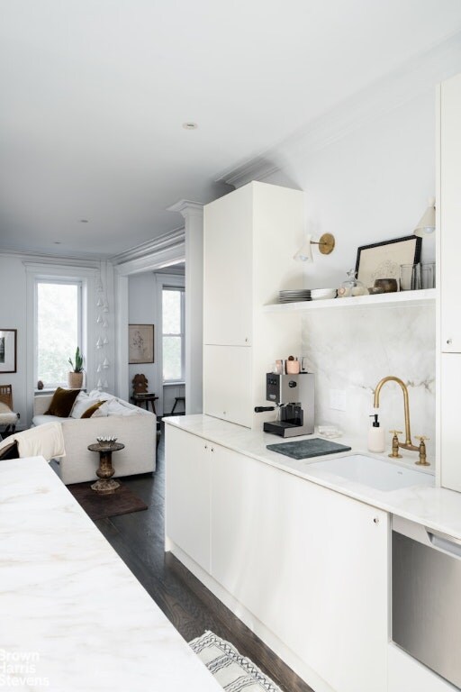 kitchen featuring sink, dark hardwood / wood-style floors, white cabinets, a kitchen bar, and built in fridge