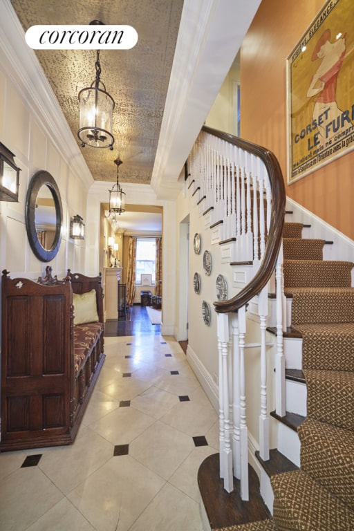 tiled entrance foyer featuring an inviting chandelier and ornamental molding