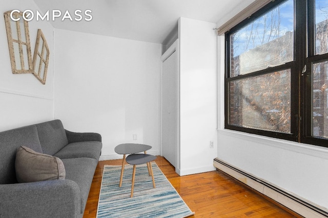 sitting room with hardwood / wood-style floors and a baseboard heating unit