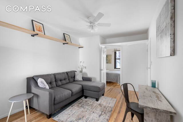 living area featuring baseboards, wood finished floors, and a ceiling fan