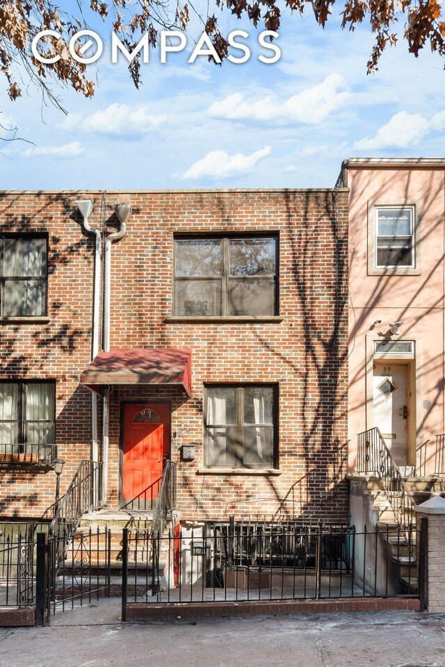 townhome / multi-family property with a fenced front yard and brick siding