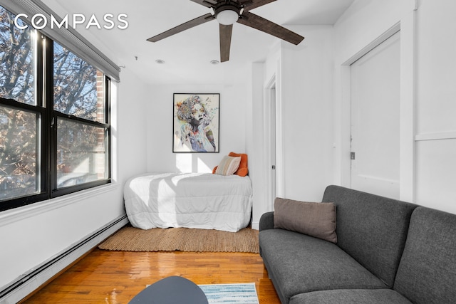 bedroom with wood finished floors, ceiling fan, and a baseboard radiator