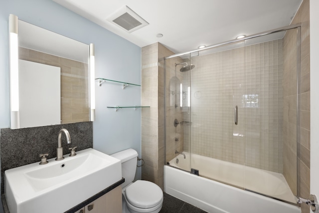 full bathroom with visible vents, vanity, toilet, and combined bath / shower with glass door