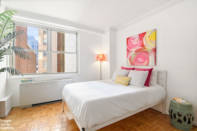 bedroom featuring crown molding, radiator, and light parquet floors