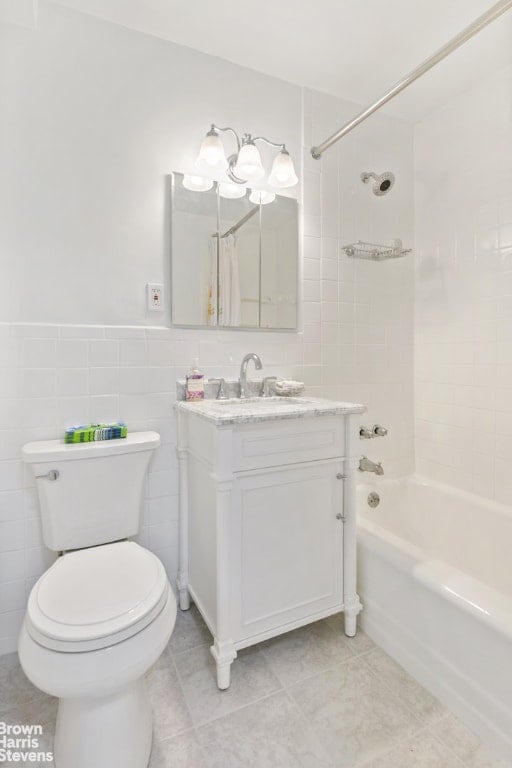 full bathroom featuring shower / tub combo with curtain, vanity, toilet, and tile walls