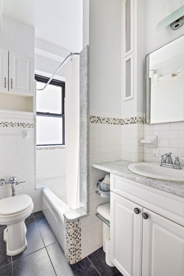 bathroom featuring shower / bath combo, toilet, tile patterned floors, vanity, and tile walls