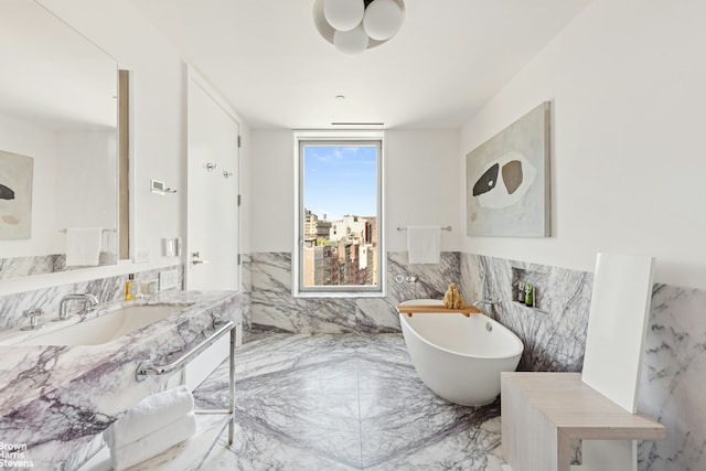 bathroom featuring a wainscoted wall, marble finish floor, a freestanding bath, vanity, and tile walls