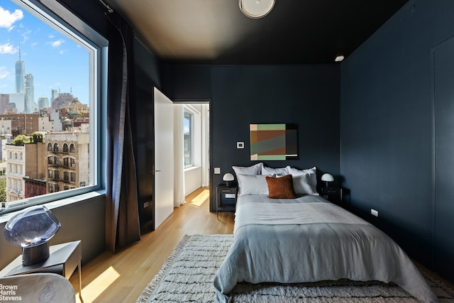 bedroom with a view of city and light wood-type flooring