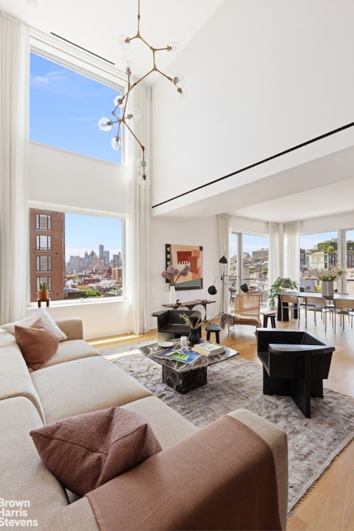 living room featuring a towering ceiling, wood-type flooring, and a chandelier