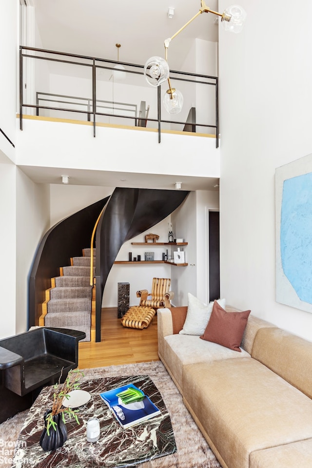 living area with stairs, a high ceiling, and wood finished floors