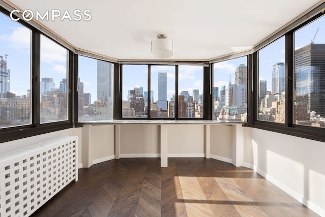 unfurnished sunroom featuring a city view and radiator heating unit