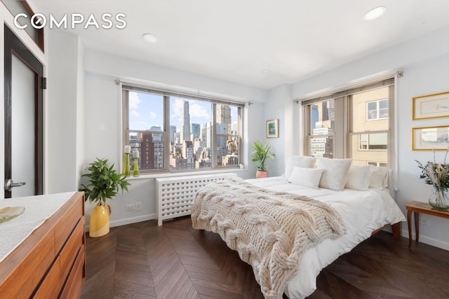 bedroom with a city view, radiator heating unit, recessed lighting, and baseboards