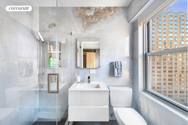 bathroom with visible vents, toilet, vanity, a shower stall, and tile walls