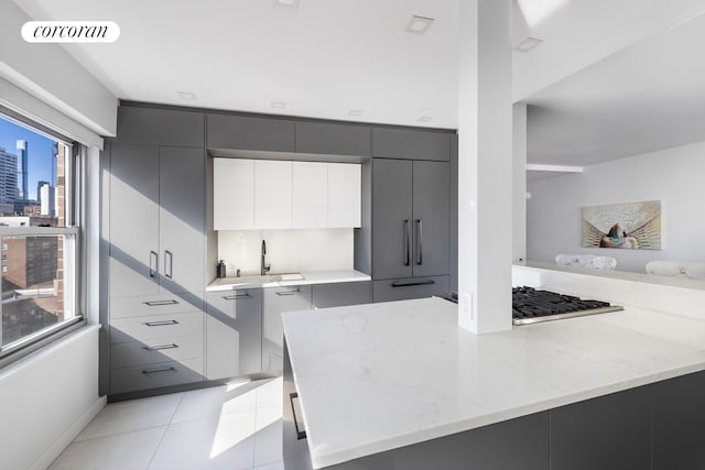 kitchen with light tile patterned flooring, visible vents, gray cabinets, light stone countertops, and modern cabinets